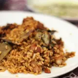 Un plato de arroz con conejo, cocinado a la perfección, con trozos de carne dorada y verduras.
