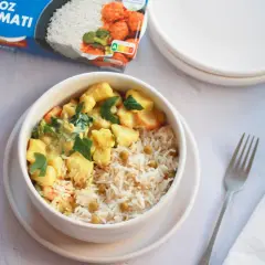 Un tazón de arroz basmati con guisantes y un curry cremoso de verduras, listo para disfrutar.