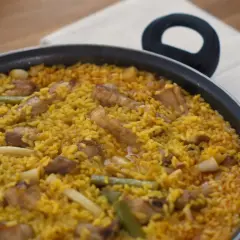 Un delicioso arroz meloso con trozos de carne, judías verdes y calamar en una paellera.