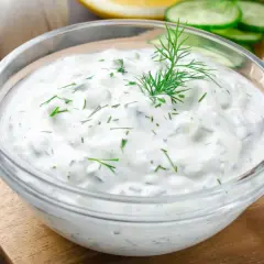 Un tazón de cremosa salsa de yogur con eneldo fresco, perfecto para untar en pan tostado.