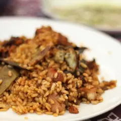 Un plato de arroz con conejo, cocinado a la perfección, con trozos de carne dorada y verduras.