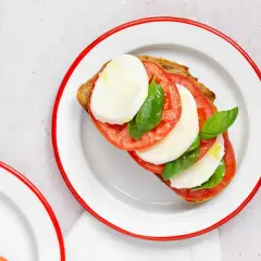 Tostada con rodajas de tomate, mozzarella fresca y albahaca, un clásico de la ensalada caprese.
