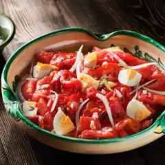 Zorongollo extremeño, una ensalada de pimientos asados, cebolla y huevo duro, servida en una cazuela de barro decorada.