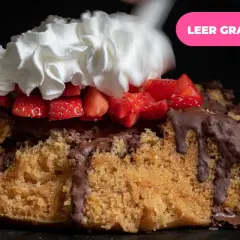 Pastel de bizcocho con chocolate derretido, fresas y una generosa porción de nata montada.