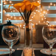 Dos copas, un jarrón con calas amarillas y una vela crean el ambiente perfecto para una velada romántica en casa.