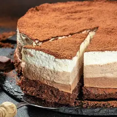 Tarta de tres chocolates, con capas de mousse de chocolate blanco, con leche y negro, espolvoreada con cacao.