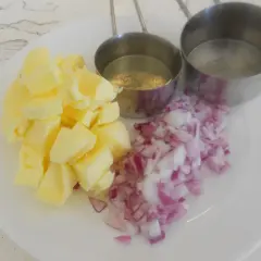 Ingredientes para un clásico beurre blanc: mantequilla en cubos, cebolla morada picada y dos recipientes con líquido.