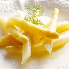 Delicados espárragos blancos, tiernos y jugosos, servidos en un plato blanco con un toque de eneldo.