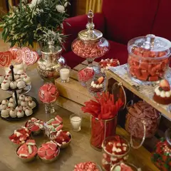 Ideas para como hacer un candy bar para boda: mesa llena de dulces rojos y blancos, pasteles, caramelos y piruletas en forma de corazón.