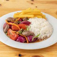 Lomo saltado con arroz blanco, papas fritas, carne, cebolla roja, tomate y cilantro. Un plato peruano delicioso.