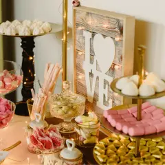 Mesa dulce con dulces variados, malvaviscos, caramelos y un cartel de "LOVE". Un candy bar original para celebrar el amor.