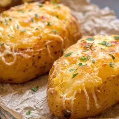 Patatas panaderas doradas y gratinadas con queso, espolvoreadas con perejil fresco.