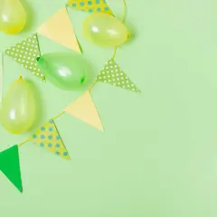 Globos y banderines de colores pastel sobre fondo verde claro, perfectos para ideas de cumpleaños.