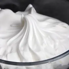 Merengue italiano esponjoso y brillante en un bol de cristal, listo para decorar postres.