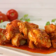 Sabroso pollo con tomate, cocinado a fuego lento hasta que esté tierno y jugoso, servido en una salsa roja vibrante.
