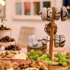 Delicioso picoteo de cumpleaños infantil con donuts, uvas, quesos y frutos secos. ¡Una mesa dulce para celebrar!