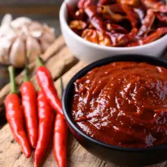 Un tazón de salsa ranchera, con chiles rojos frescos, secos y ajo alrededor.