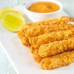 Crujientes gambas a la gabardina doradas, servidas con rodajas de lima y una salsa cremosa.