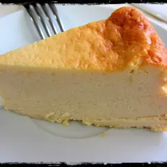 Una rebanada de tarta de queso Philadelphia, con su superficie dorada y cremosa textura, lista para ser disfrutada.