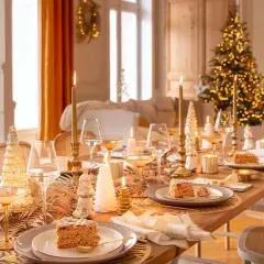 Elegantes mesas decoradas de navidad con velas doradas, copas de champán y postres festivos, creando un ambiente cálido y acogedor.