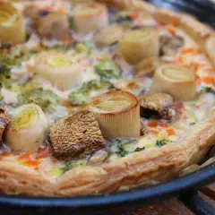Quiche de verduras recién horneada, con puerros, brócoli y champiñones, lista para disfrutar.