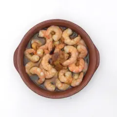 Gambas al pil pil burbujeantes en cazuela de barro, con ajo y aceite de oliva.
