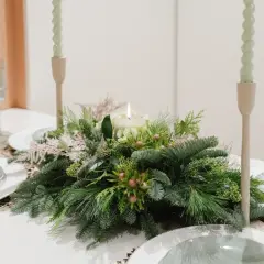 Centros de mesa de navidad sencillas con velas y follaje verde. Copas y platos listos para una cena festiva.