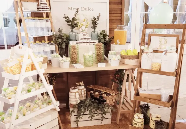 Mesa dulce con dulces, botellas de agua y un dispensador de jugo. Ideas para como hacer un candy bar.