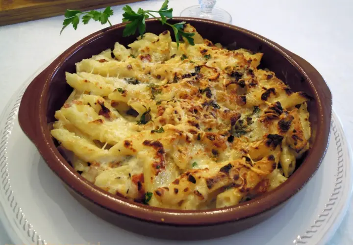 Macarrones con queso gratinados, burbujeantes y dorados, listos para servir. Un plato reconfortante y delicioso.