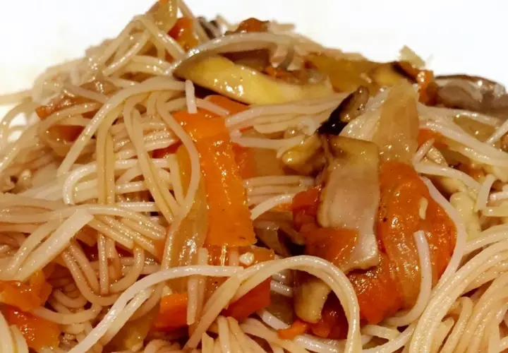 Un plato de fideos de arroz salteados con zanahoria y champiñones, un festín para los sentidos.