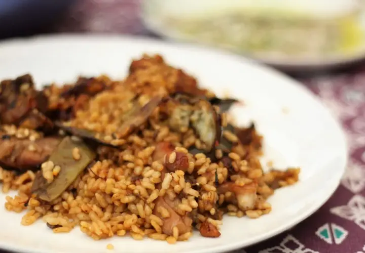 Un plato de arroz con conejo, cocinado a la perfección, con trozos de carne dorada y verduras.