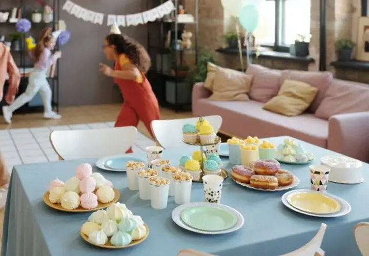 Niños corriendo en fiesta infantil. Mesa con pastel, donas, cupcakes y dulces. ¡Una guía perfecta de como organizar un cumpleaños infantil!