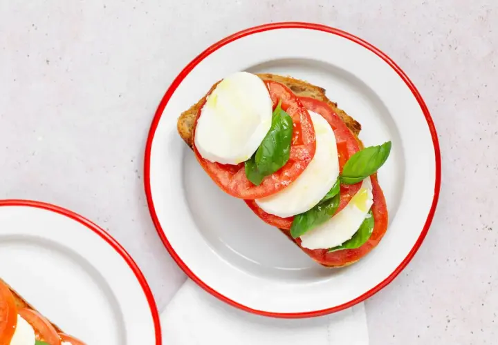Tostada con rodajas de tomate, mozzarella fresca y albahaca, un clásico de la ensalada caprese.