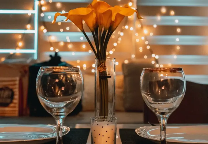 Dos copas, un jarrón con calas amarillas y una vela crean el ambiente perfecto para una velada romántica en casa.