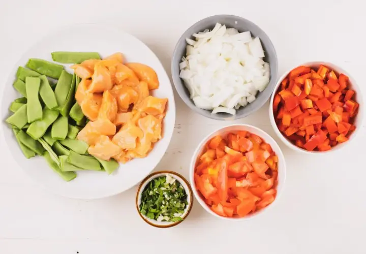 Ingredientes para fideuá de pollo: trozos de pollo, judías verdes, cebolla, pimiento rojo, tomate y perejil picado.