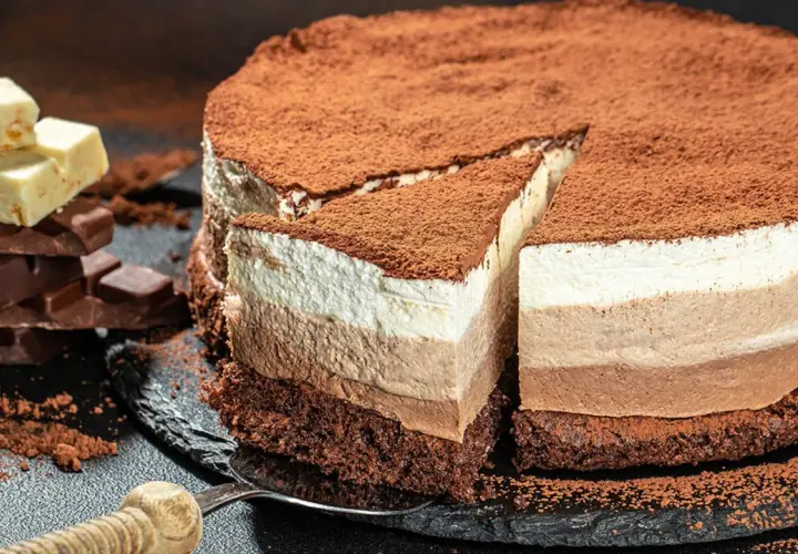 Tarta de tres chocolates, con capas de mousse de chocolate blanco, con leche y negro, espolvoreada con cacao.