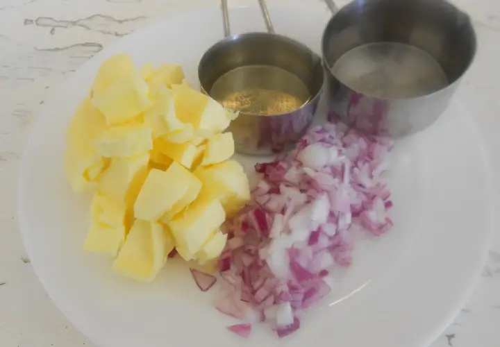 Ingredientes para un clásico beurre blanc: mantequilla en cubos, cebolla morada picada y dos recipientes con líquido.