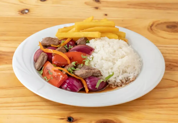 Lomo saltado con arroz blanco, papas fritas, carne, cebolla roja, tomate y cilantro. Un plato peruano delicioso.