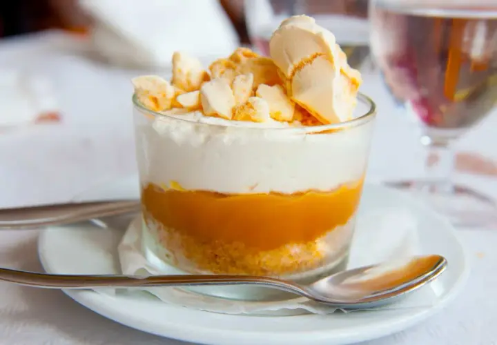Delicioso postre en vaso con capas de galleta, dulce de leche y crema, coronado con merengue crocante. Un polvito uruguayo que invita a disfrutar.