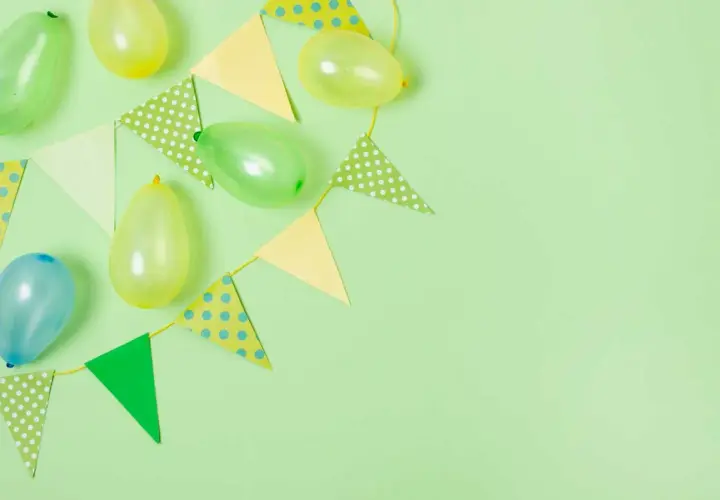 Globos y banderines de colores pastel sobre fondo verde claro, perfectos para ideas de cumpleaños.