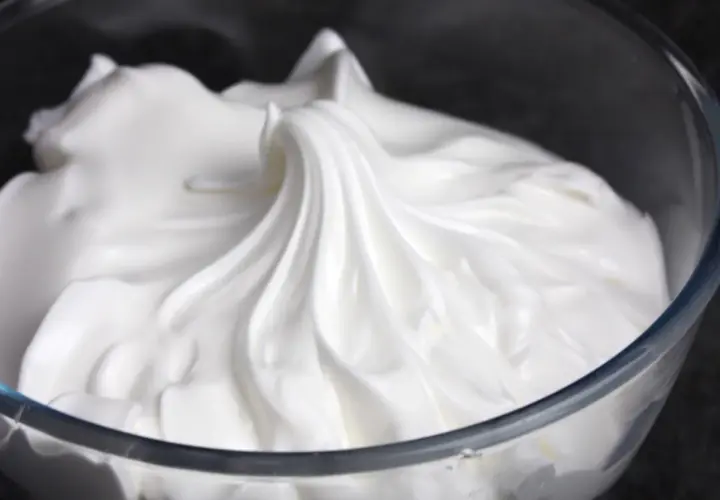 Merengue italiano esponjoso y brillante en un bol de cristal, listo para decorar postres.