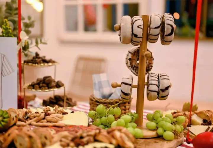 Delicioso picoteo de cumpleaños infantil con donuts, uvas, quesos y frutos secos. ¡Una mesa dulce para celebrar!