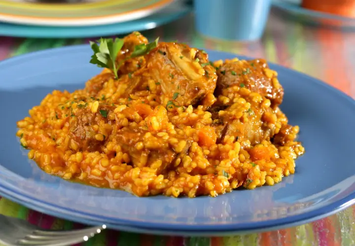 Arroz con costillas, un plato reconfortante con trozos de carne tierna y arroz amarillo, decorado con perejil fresco.