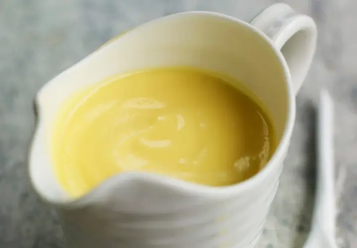 Crema amarilla y sedosa en una salsera blanca, lista para realzar cualquier plato. Es la clásica salsa holandesa.