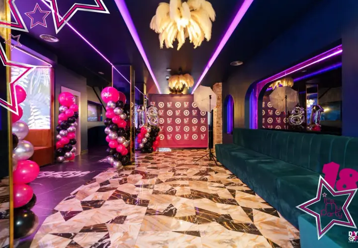 Decoración espectacular con globos rosas, negros y plateados, luces neón y un sofá verde. ¡Ideas para fiesta de 18 años mujer!
