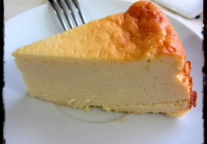 Una rebanada de tarta de queso Philadelphia, con su superficie dorada y cremosa textura, lista para ser disfrutada.
