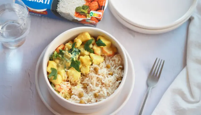Un tazón de arroz basmati con guisantes y un curry cremoso de verduras, listo para disfrutar.