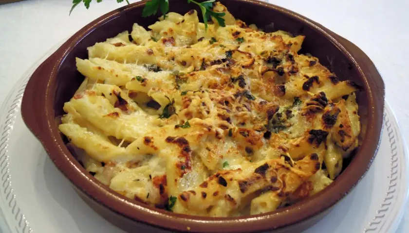 Macarrones con queso gratinados, burbujeantes y dorados, listos para servir. Un plato reconfortante y delicioso.