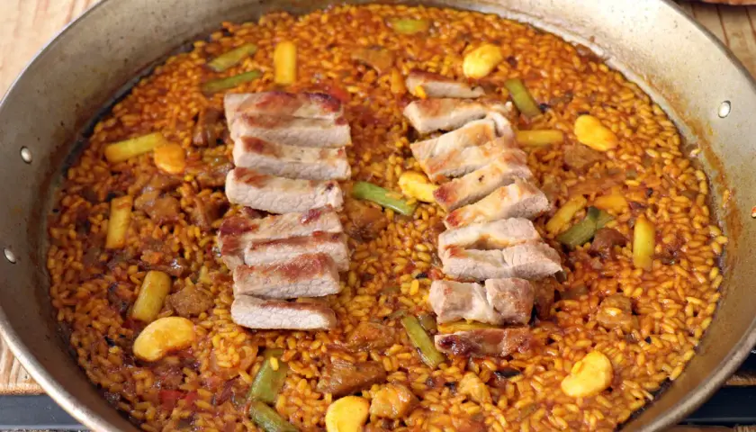 Paella de arroz con secreto ibérico, jugoso y lleno de sabor.