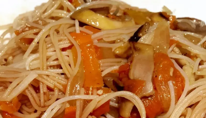 Un plato de fideos de arroz salteados con zanahoria y champiñones, un festín para los sentidos.